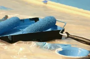 A paint roller in a paint tray with blue paint