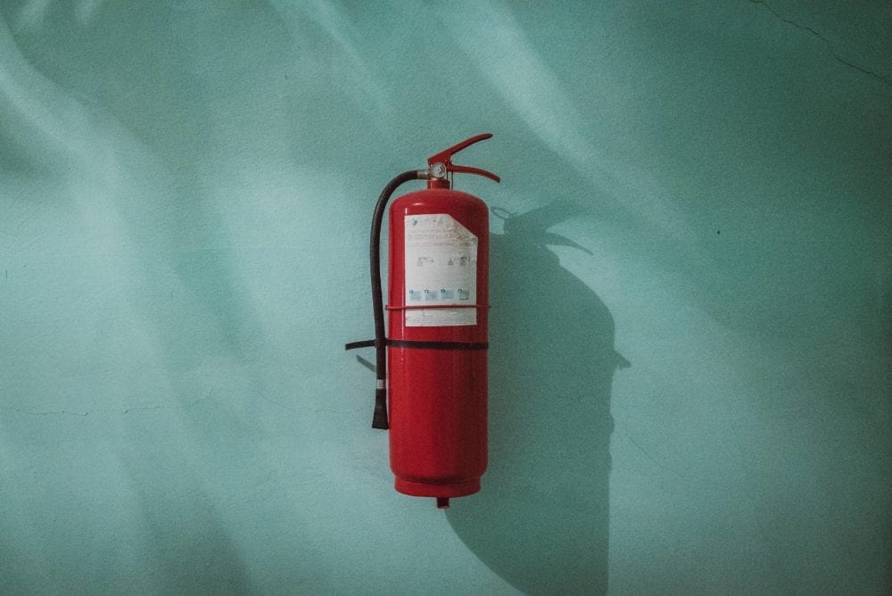 A fire extinguisher on a teal wall