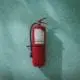 A fire extinguisher on a teal wall