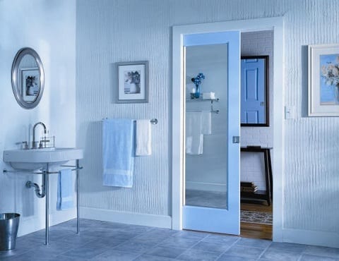 Mirrored pocket door with white frame sliding into wall between bathroom and hallway