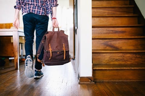 man walking out of home with moving bag in hand