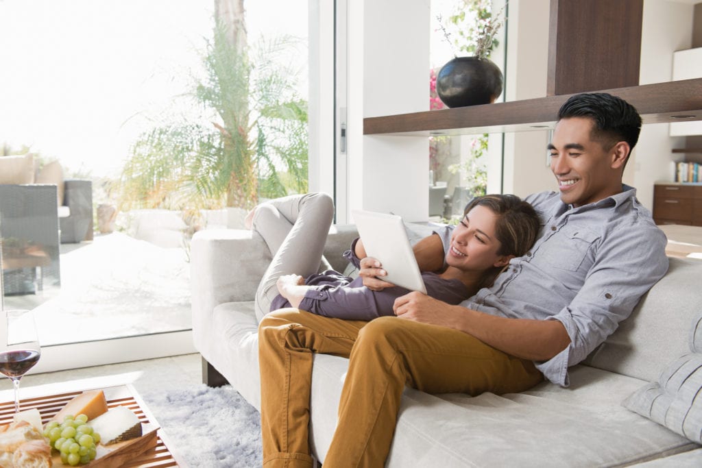 Couple researches online on tablet for design ideas for their living room