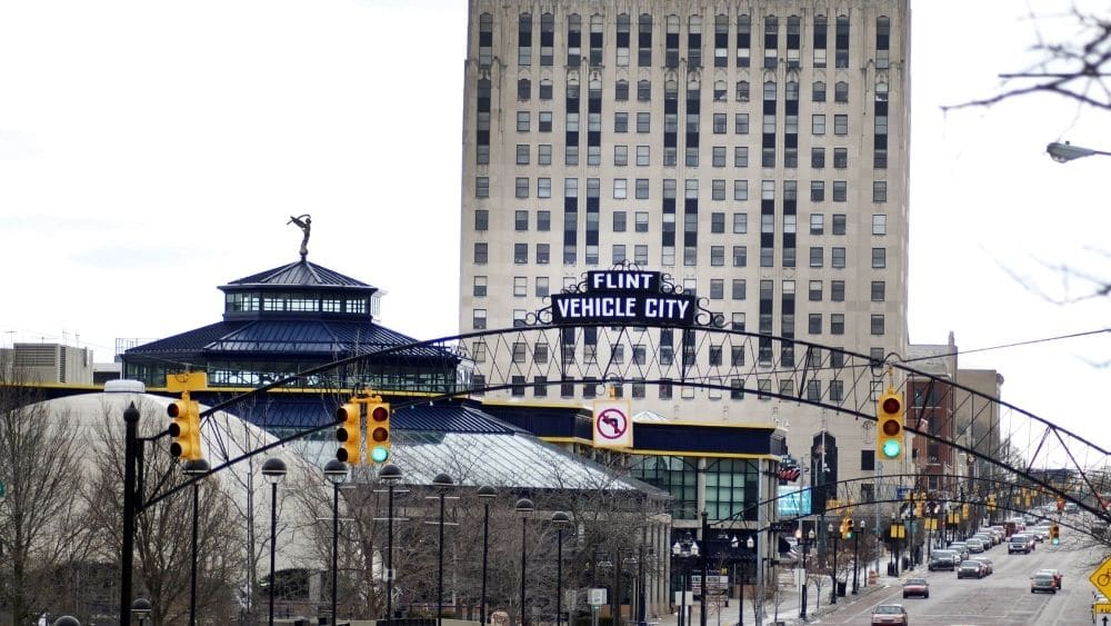 welcome sign over road that says "Flint Vehicle City"