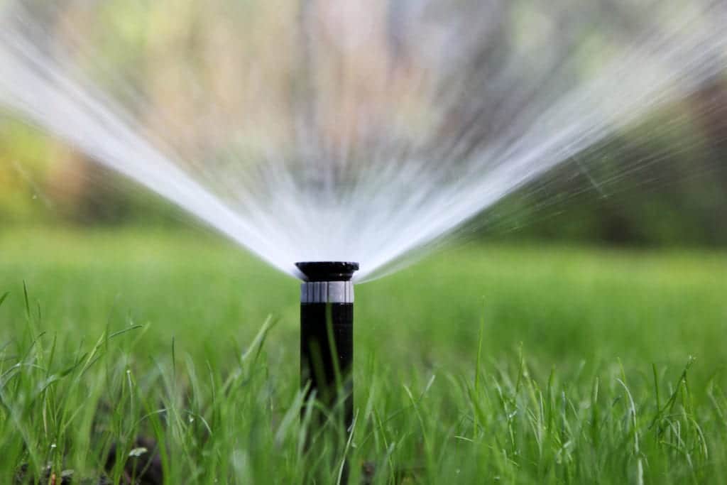 Sprinkler system watering a green lawn