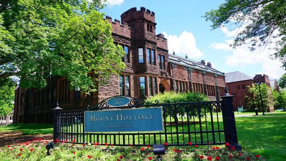 fence that says mount holyoke college with an old building in the back