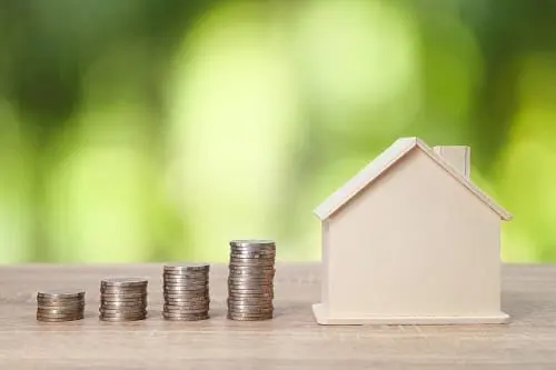 Increasing stacks of quarters, culminating in a home