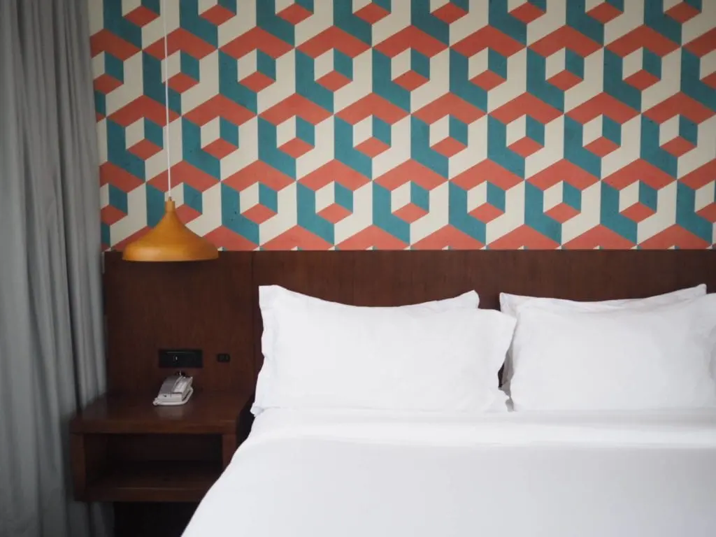 Patterned wallpaper over bright white bedding.