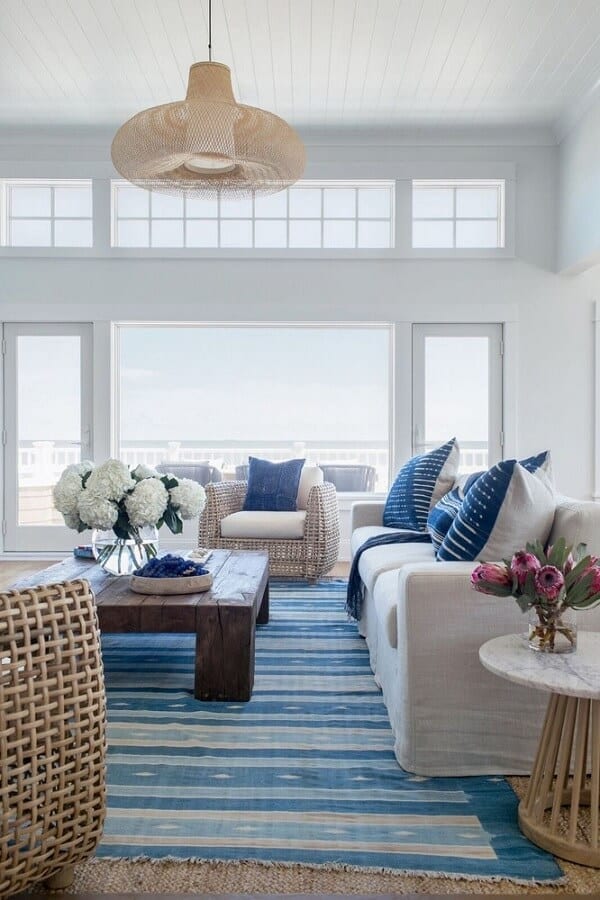 White living room with rich blue accents and lots of natural light coming in through large glass windows