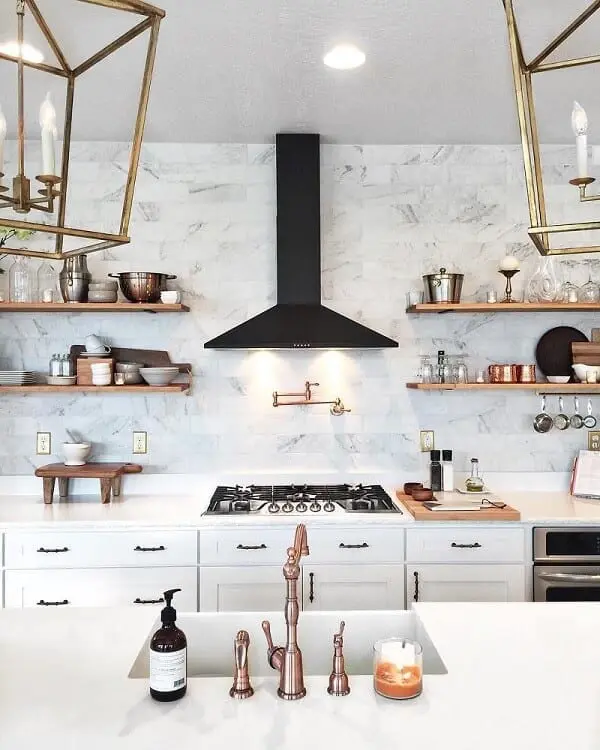 Kitchen with white cabinets, black hood, and hardware in different tones of gold