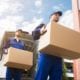 Movers carrying cardboard boxes out of moving van