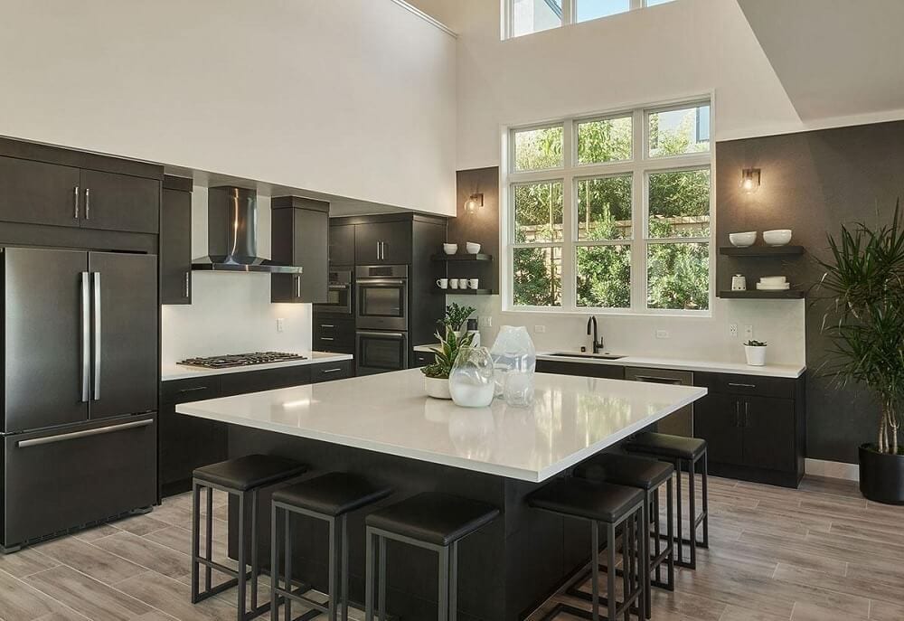Modern, monochrome kitchen with a large island and black cabinetry and appliances