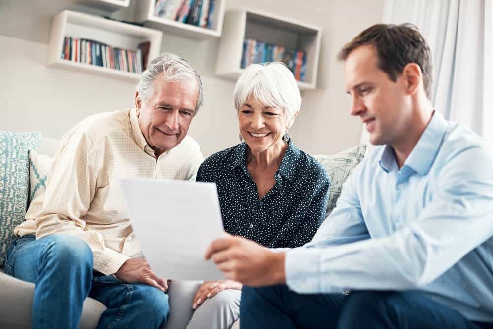 Senior couple and real estate agent looking at document