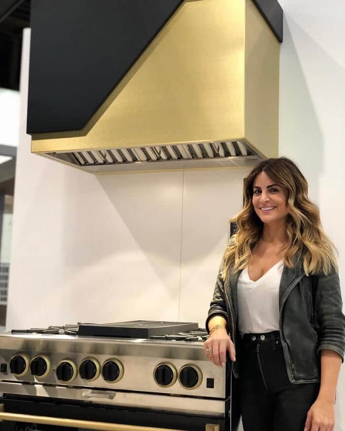 Woman standing next to a gold and black range hood