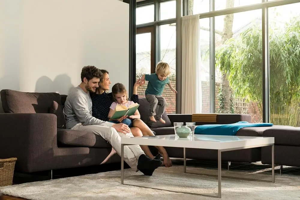 Young family of four having fun together in modern living room