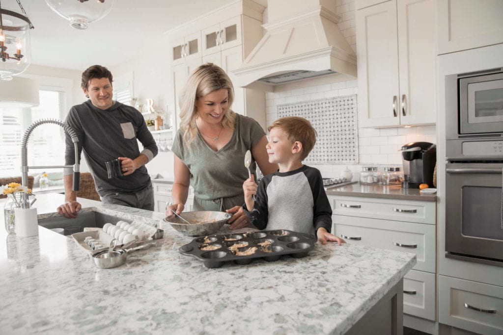 Family baking muffins in the kitchen of a new home on a granite countertop