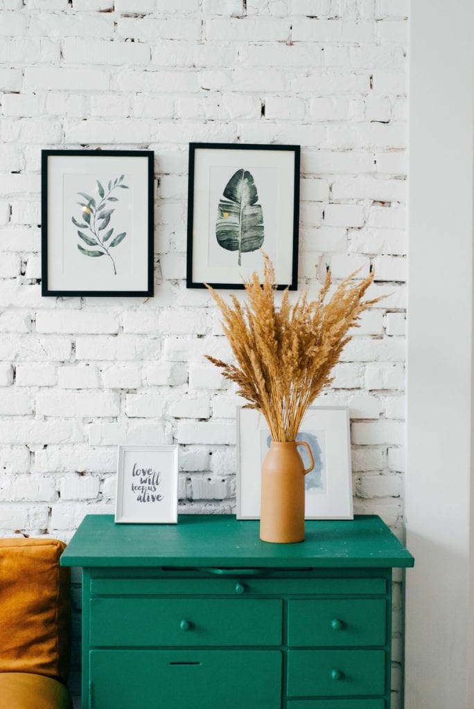 Green dresser in front of white brick wall