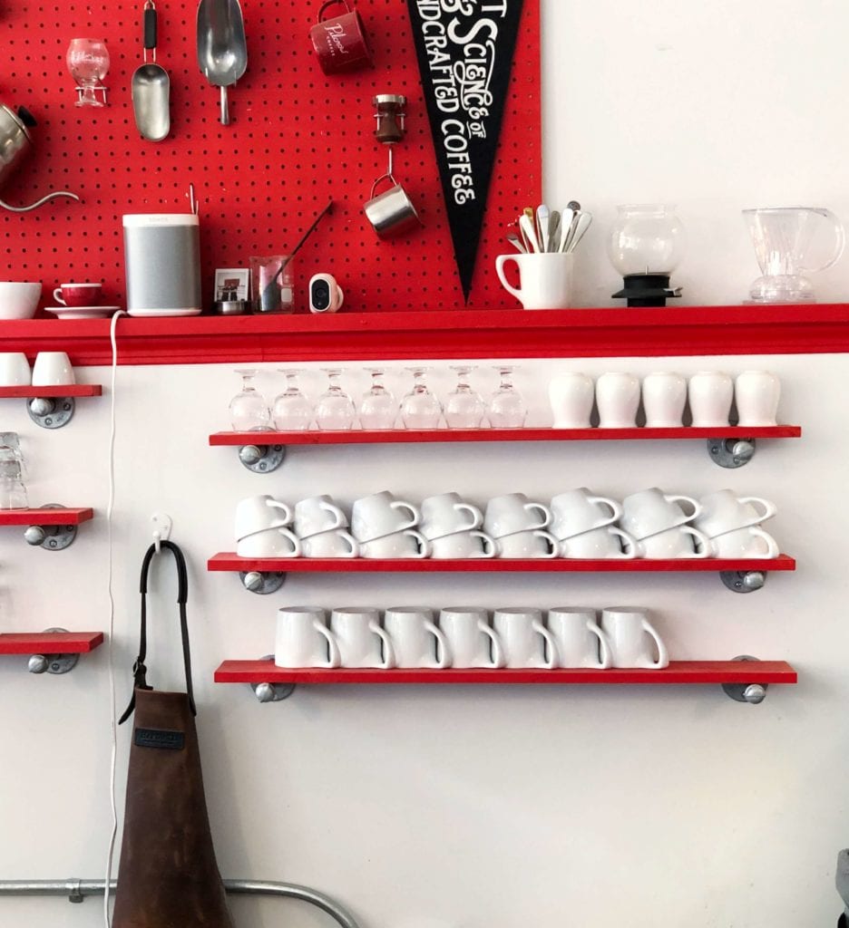 White mugs and glasses on red shelf