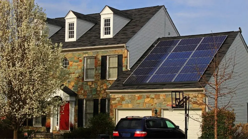 Two story home with solar panels on the roof of the garage.