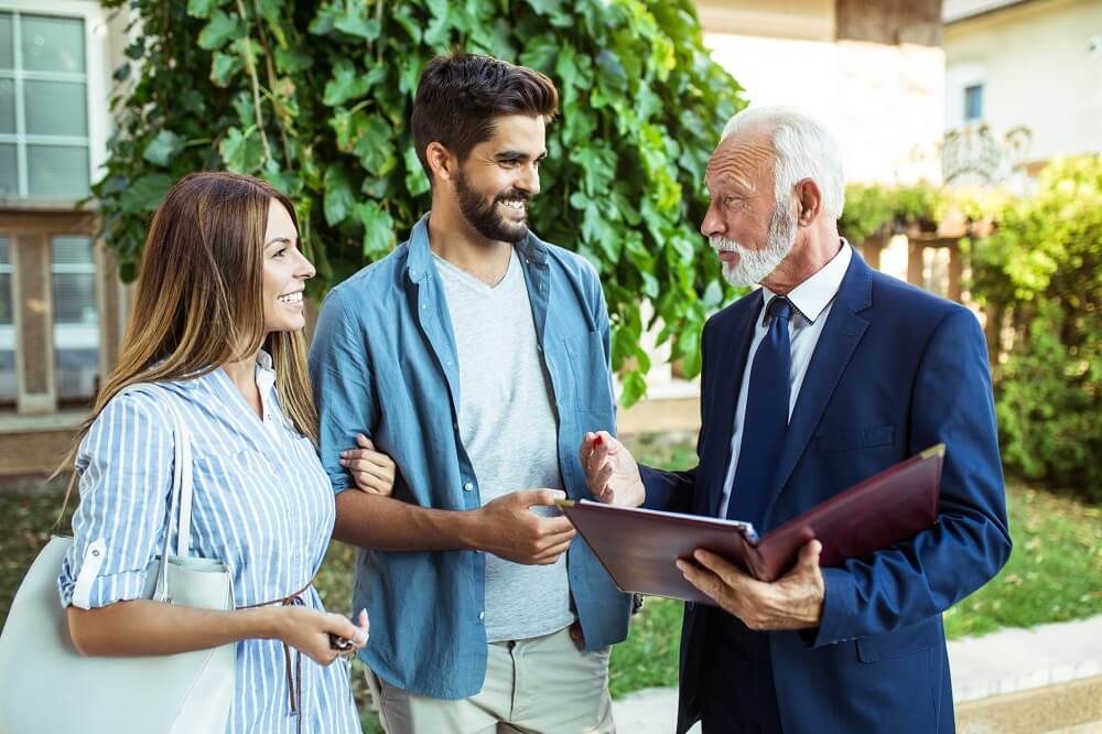 realtor-speaking-with-couple-outside-of-home