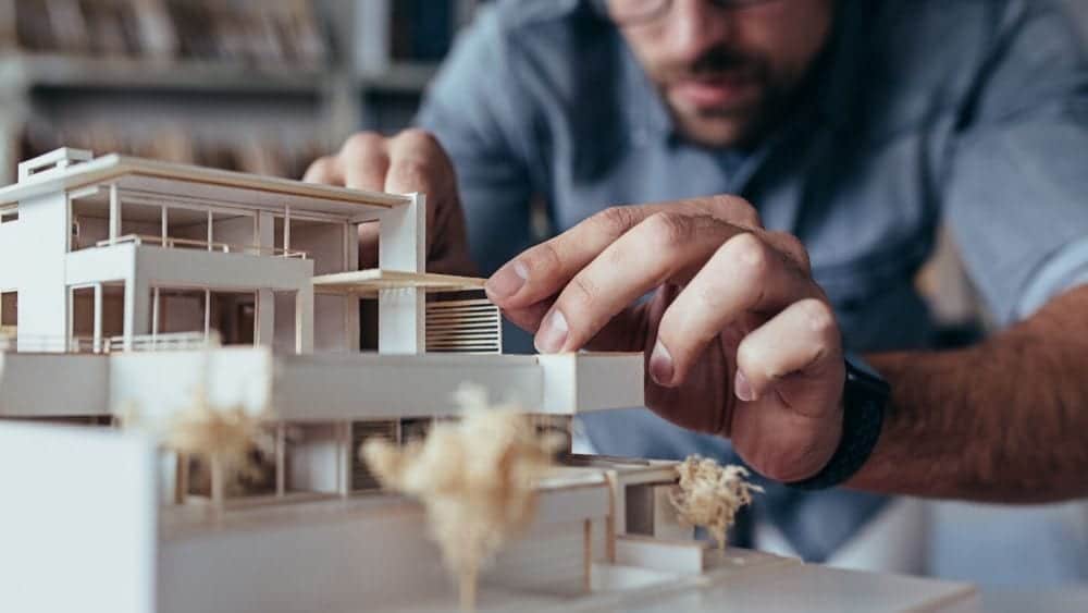 Close up of an architect working on a model of a home.
