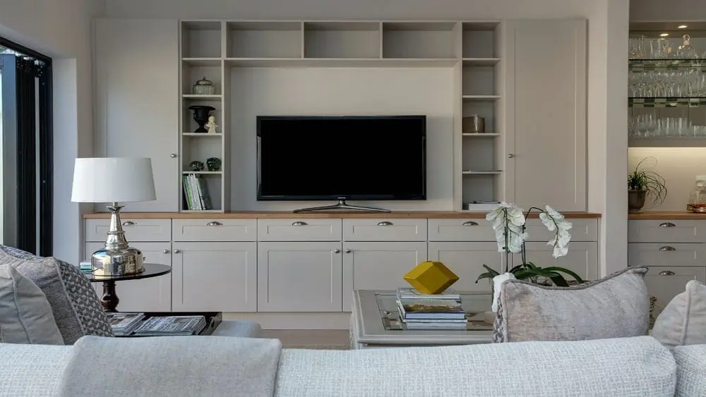 interior image of a living room with white wall and storage unit and flat screen tv