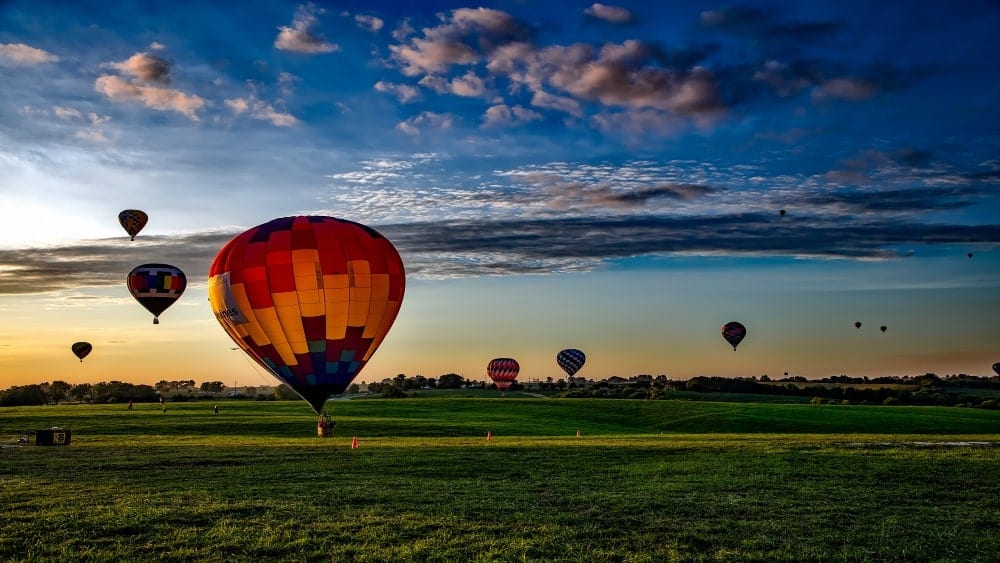 Hot air balloon rise in an Iowa field with a sunrise in background