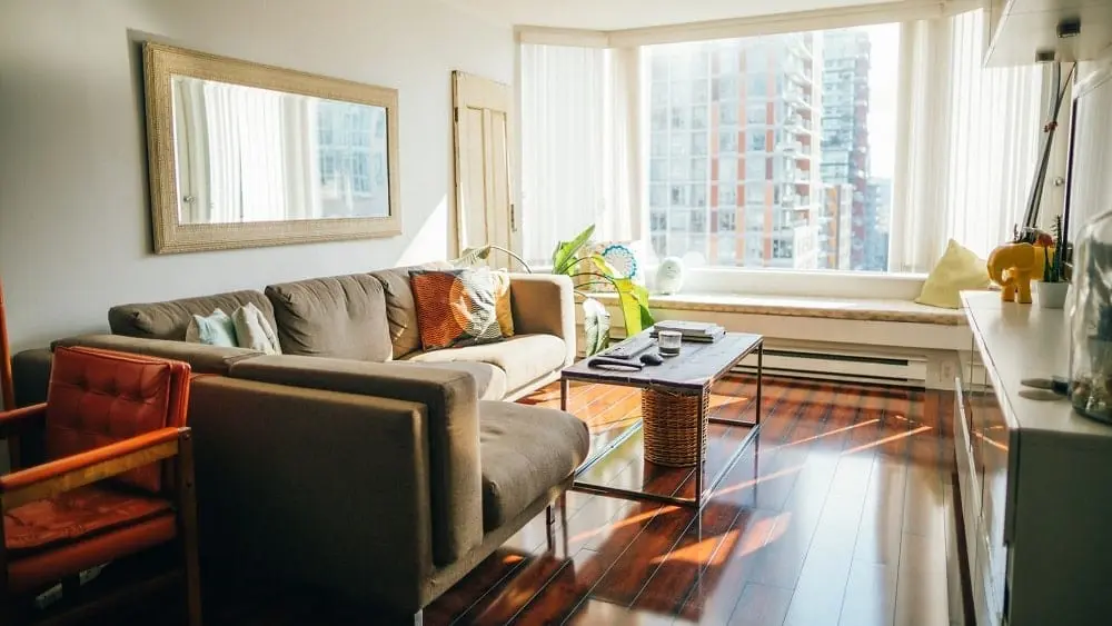Neutral living room with a large window displaying a high-rise building outside.