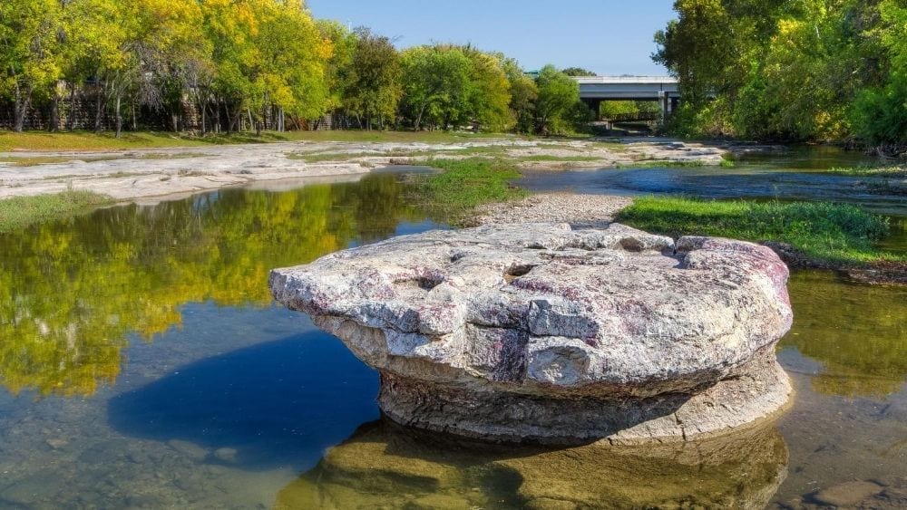 A round rock in a river bed; Round Rock's namesake.