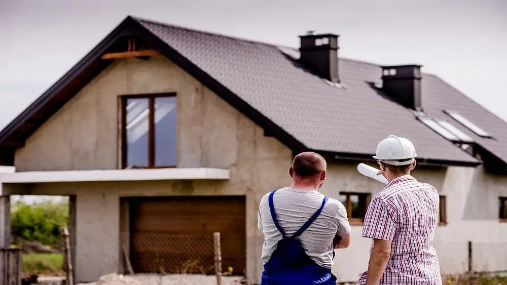 Two builders looking at house in the background.