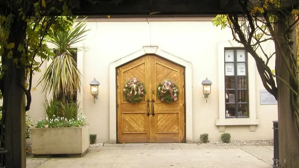 A close up of wooden double doors with wreaths on them.