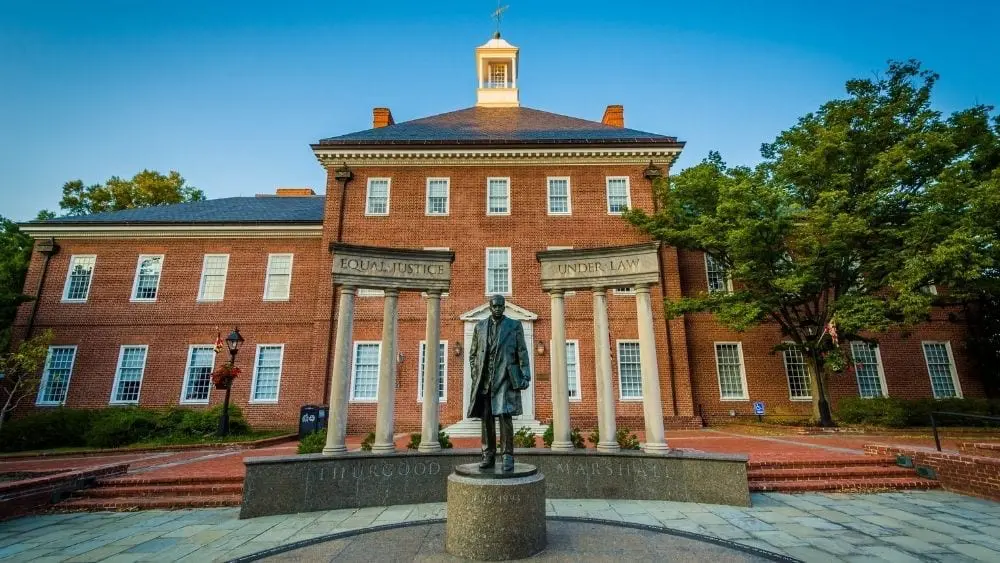 A bronze statue paying respect to Thurgood Marshall in front of an American colonial building.