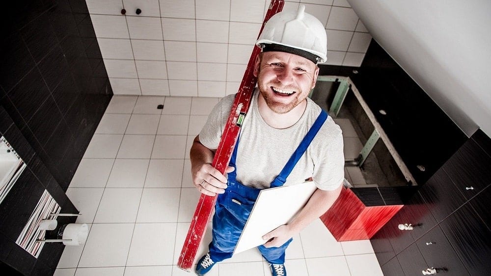 A smiling builder holding construction materials.