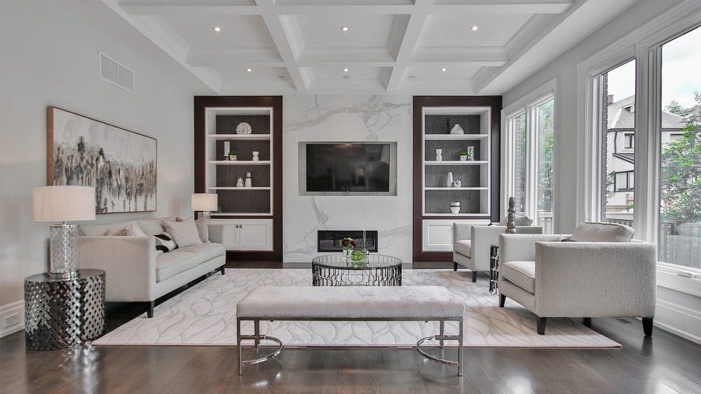 Luxurious monochrome living room with white furniture, silver accents, flat screen TV and fireplace.