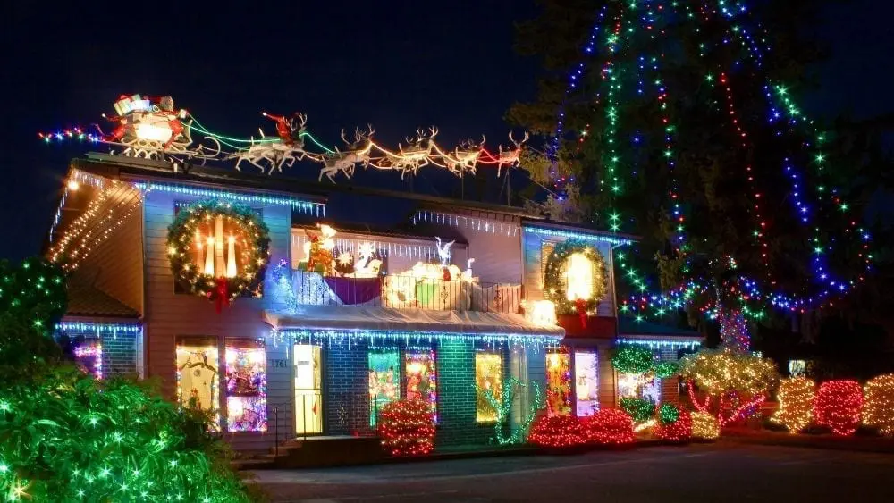 A two-story home viewed from in angle covered in lots of colorful Christmas lights.