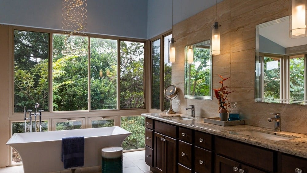 Luxurious bathroom with double vanity, large windows, and freestanding bathtub.