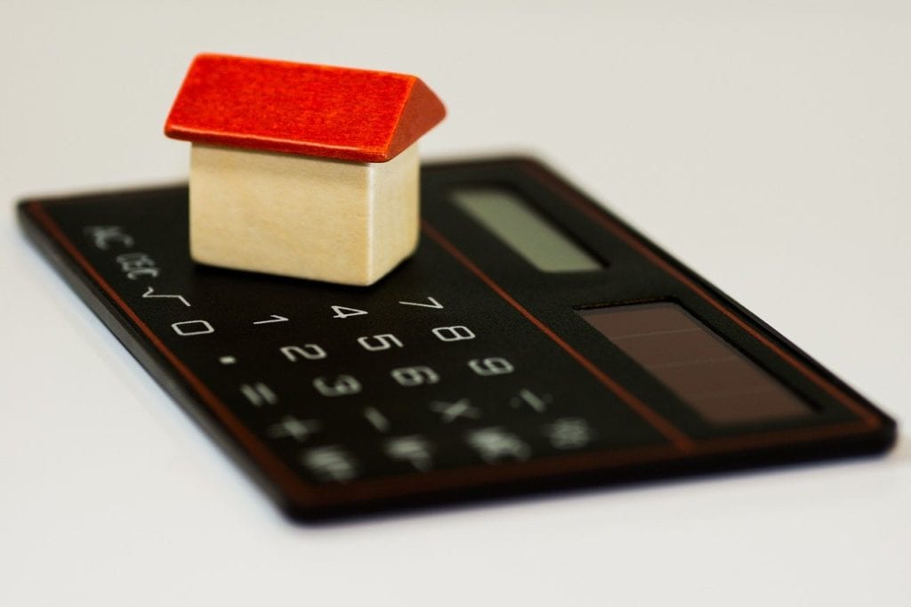 Miniature house on top of a calculator.