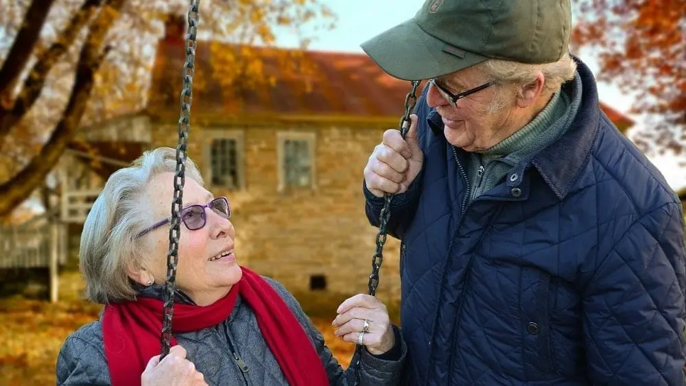 Older couple outside house on a swing.