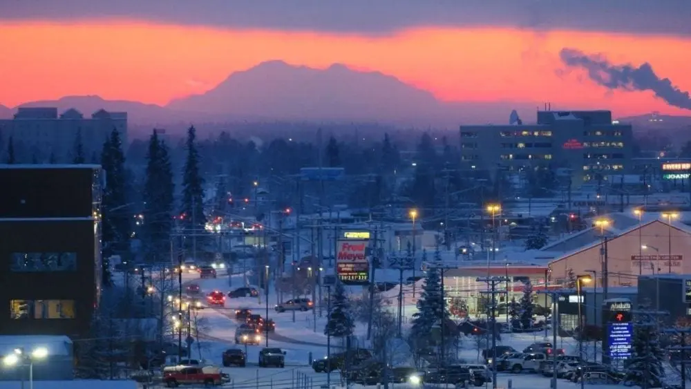 A town covered in snow with a mountain and pink sky in the background.