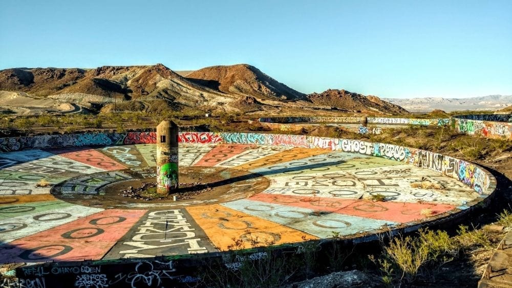 Graffiti art meant to look like a massive roulette wheel, set in the desert with mountains in the background.