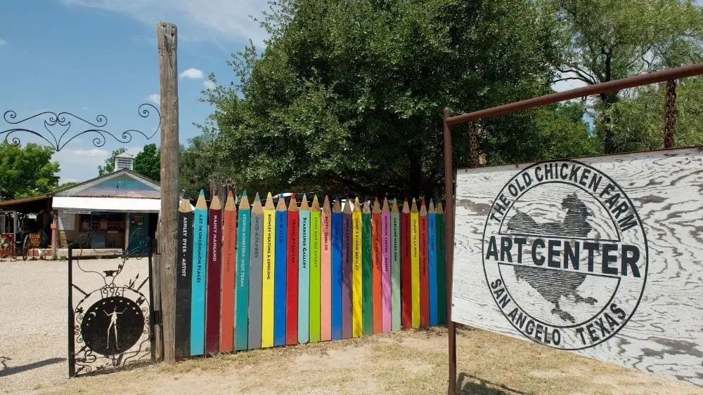A colorful fence next to a sign reading "The Old Chicken Farm Art Center."