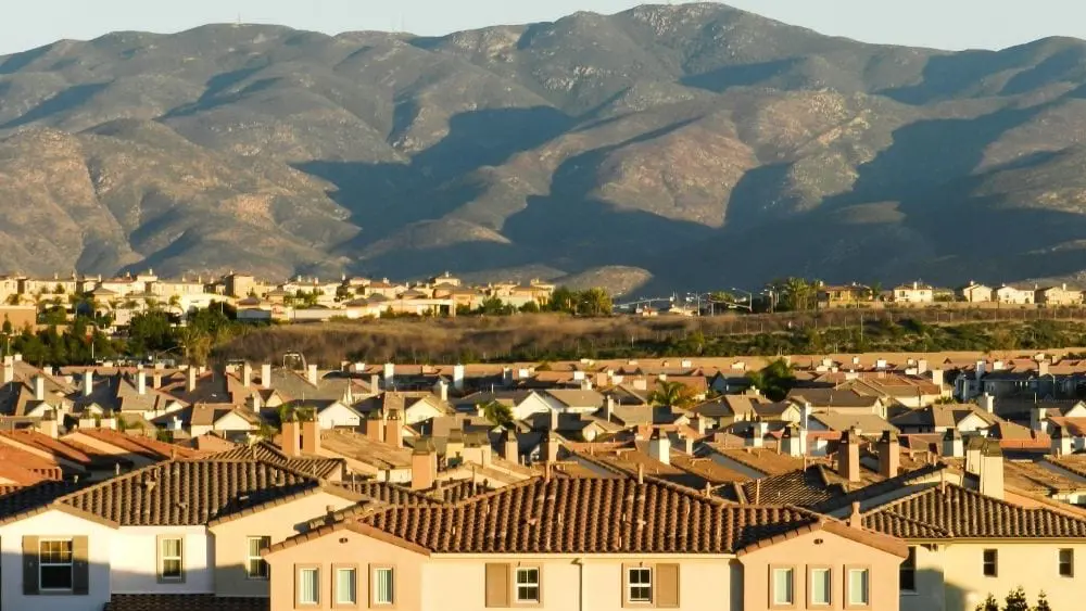 Aerial view of Spanish-style homes in a valley in front of a mountain range.