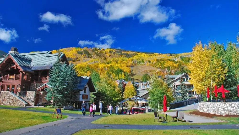 A colorful mountain range in the fall, with yellow and green trees dotting the sides.