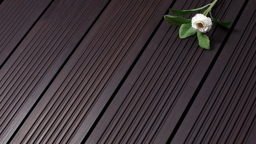 Close shot of dark bamboo flooring with a flower laid on top.