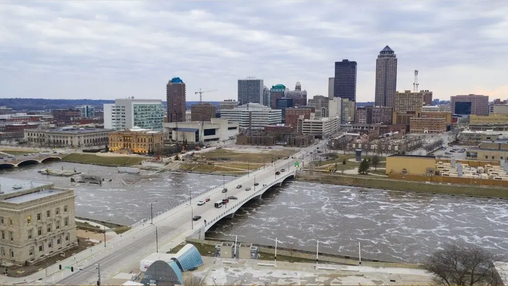 A winter day showing a bridge crossing a fast-moving river and leading into a city.