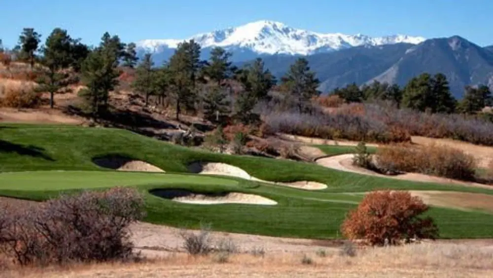 A well-maintained golf course with a snow-capped mountain in the background.
