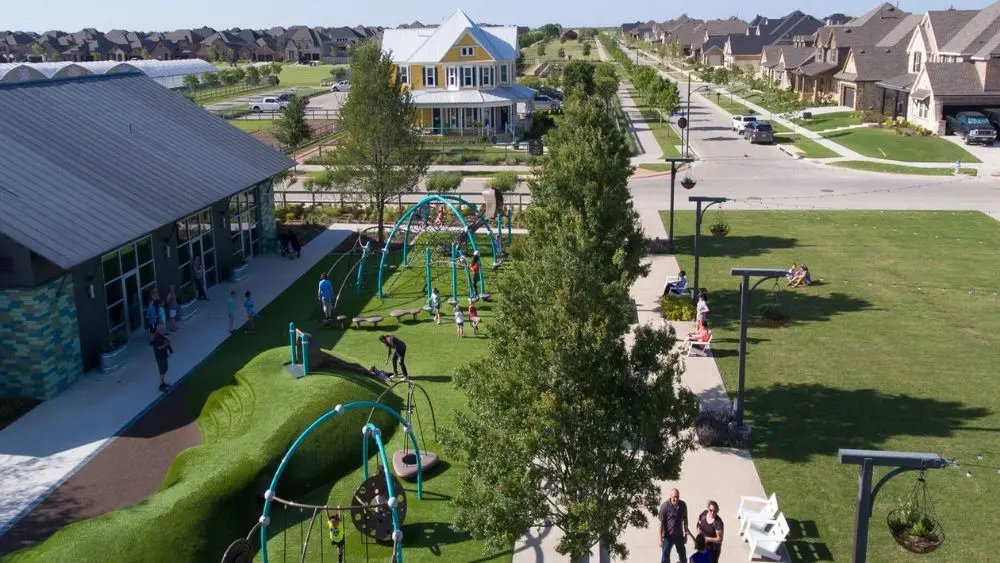 Community playground with lots of greenspace and families walking along the paths.