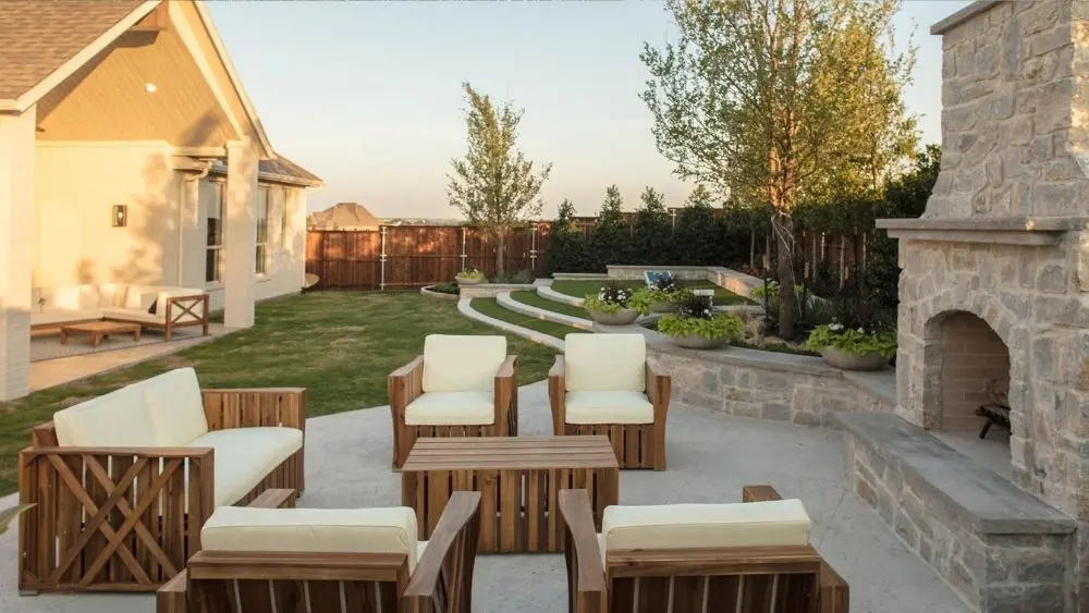 Backyard with a manicured lawn, fireplace, and seating area.