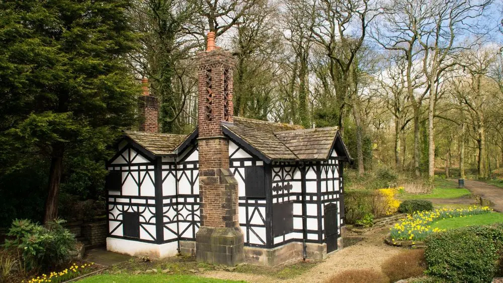 A Tudor cottage on a sunny day in an open field.