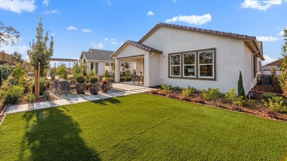 A house with white-stucco walls and a well-manicured lawn.