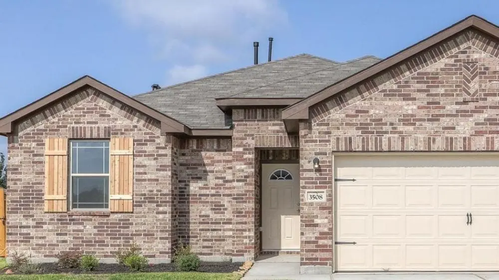 A single-story suburban home made from brown brick with a cream-colored garage door.